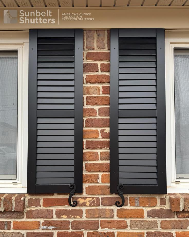 Black composite louvered shutters on a brick home