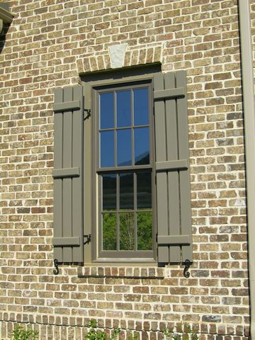 Olive open board and batten shutters on a stone home, with shutter dogs.