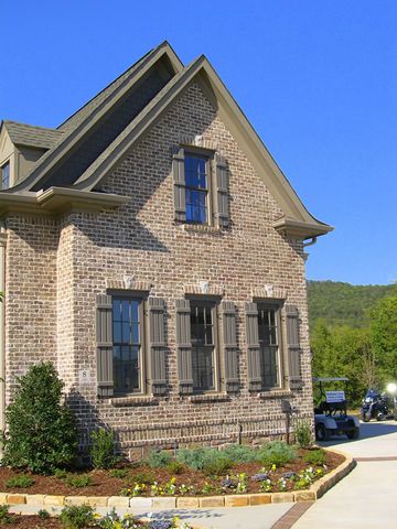 Brick home with taupe open board and batten shutters on the gable and side windows.