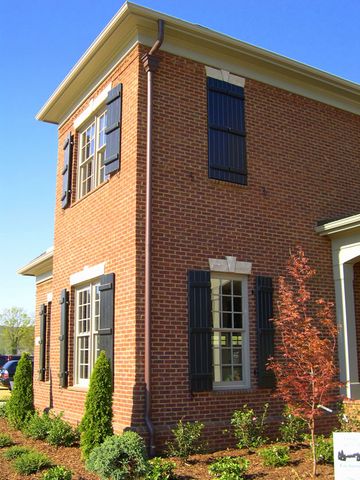 Two-story brick home with black open board and batten shutters.