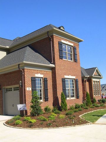 Corner view of a brick home with black closed board and batten shutters on every window.