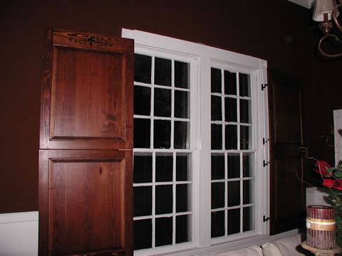 Dark-stained flat panel shutters on a French door, interior view.