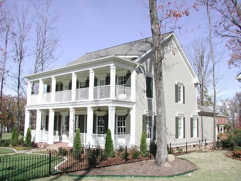 Two-story Southern home with double porches and dark green louvered shutters on every window.