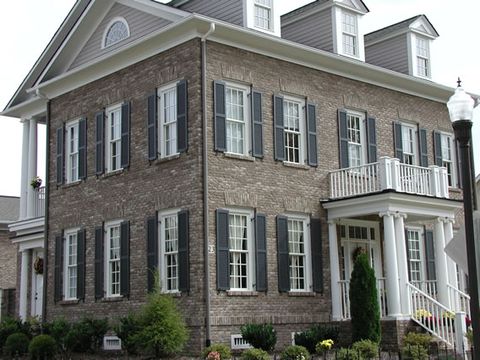 Three-story brick Georgian with black louvered shutters on every window.