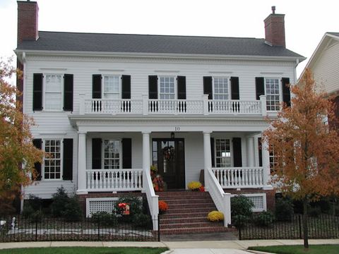 White two-story home with black louvered shutters and a double porch.