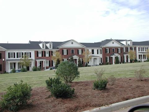Row of new brick and clapboard homes, all fitted with black louvered shutters.