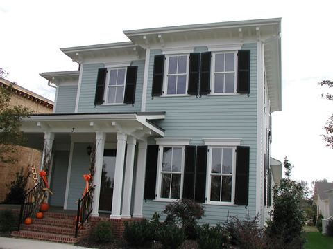 Light blue two-story home with black louvered shutters and a columned porch.