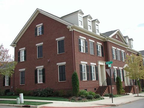 Red brick corner townhome with black louvered shutters on three floors.