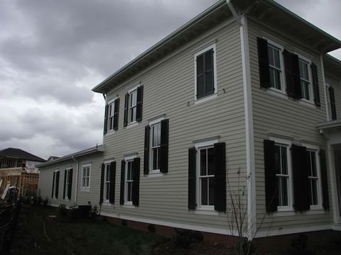 Cream two-story home with black louvered shutters, side elevation.