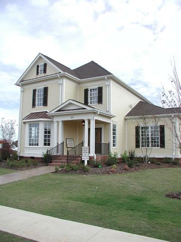 Pale yellow two-story with dark louvered shutters and a covered entry.