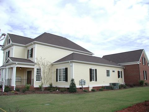 Pale yellow two-story home with dark louvered shutters, rear elevation.