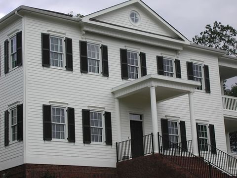 Cream two-story with black louvered shutters and a two-story entry porch.