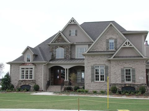 Brick and stone home with sage open board and batten shutters, front elevation.