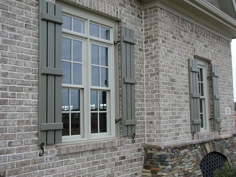 Sage open board and batten shutters on a pair of brick windows, with S-scroll shutter dogs.