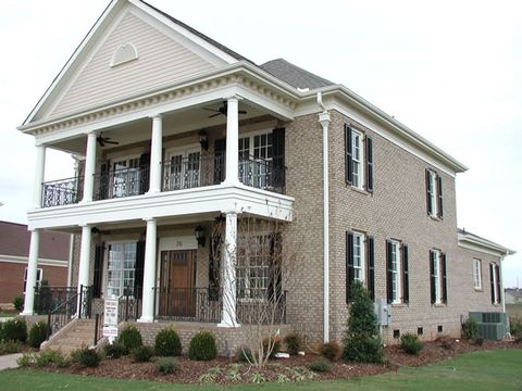 Tan brick two-story with black louvered shutters and a two-story columned porch.