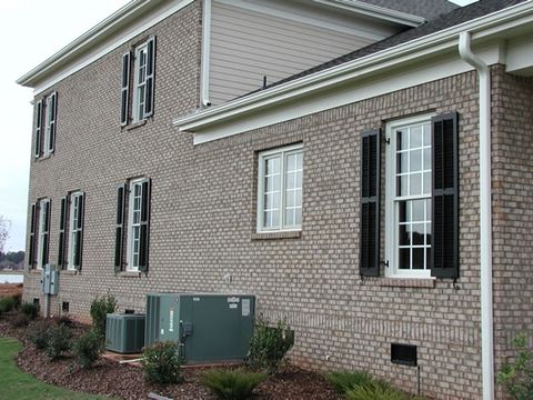 Tan brick two-story with black louvered shutters, side elevation.