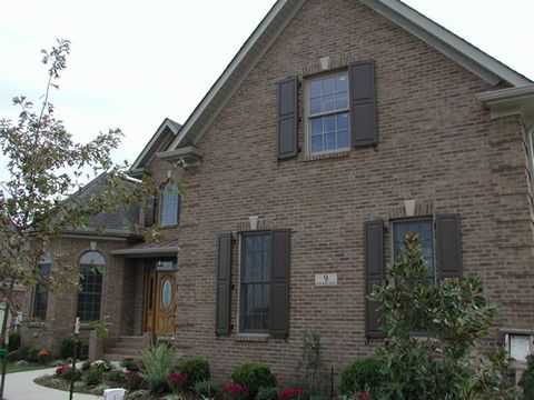 Brick home with charcoal flat panel shutters on the front windows and gable.
