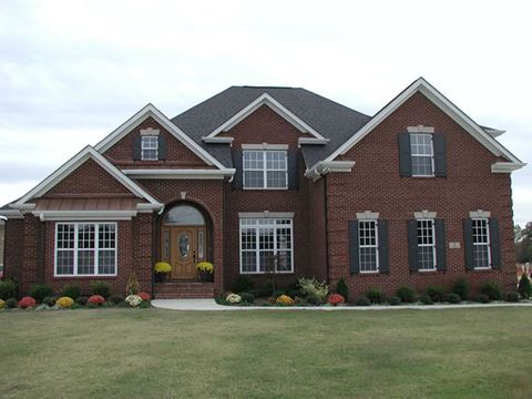 Red brick home with charcoal flat panel shutters and an arched entry, front elevation.