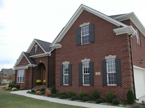 Red brick home with charcoal flat panel shutters, front and side windows.