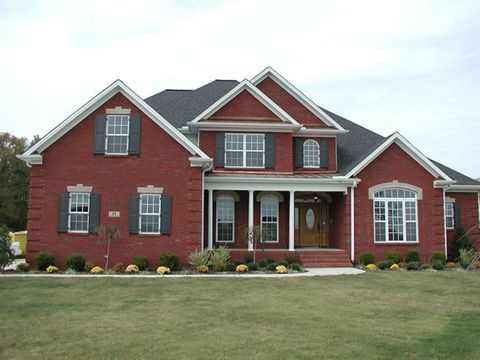 Red brick home with charcoal flat panel shutters on every window, columned entry.