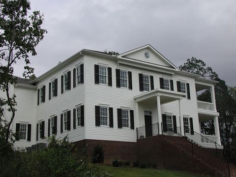 White two-story home with dark louvered shutters and a two-story columned entry.
