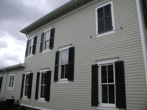 Grey two-story home with black louvered shutters, side elevation.