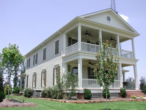 Cream two-story with olive louvered shutters and a double porch.