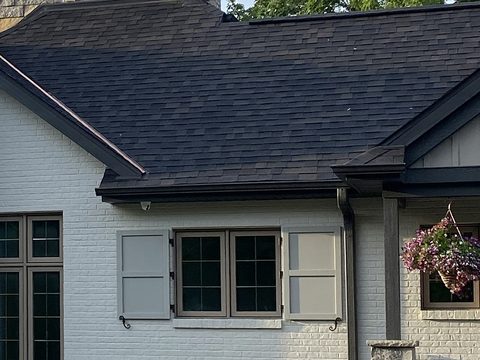 Light gray composite flat panel shutters on a white-painted brick ranch, with S-scroll shutter dogs.
