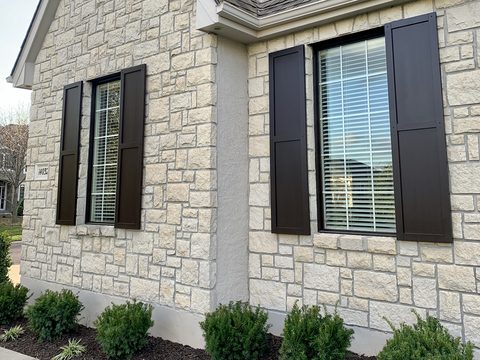 Dark brown composite flat panel shutters on a limestone and stucco home.