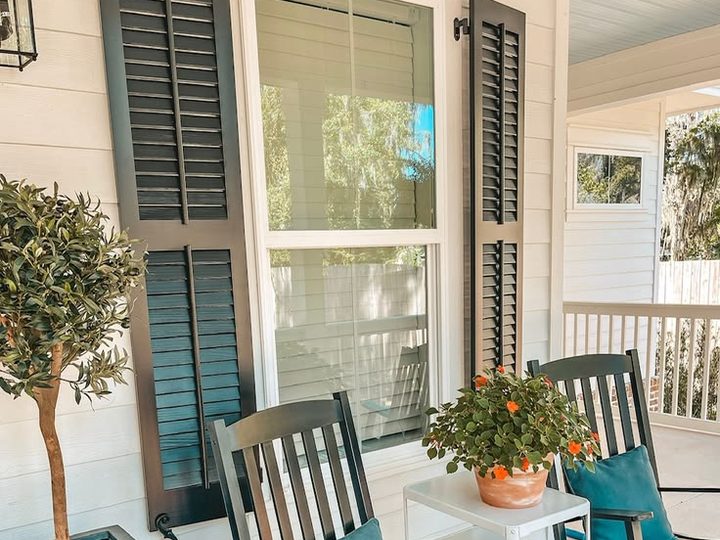 Black custom wood louvered shutters with tiebacks on a white front porch