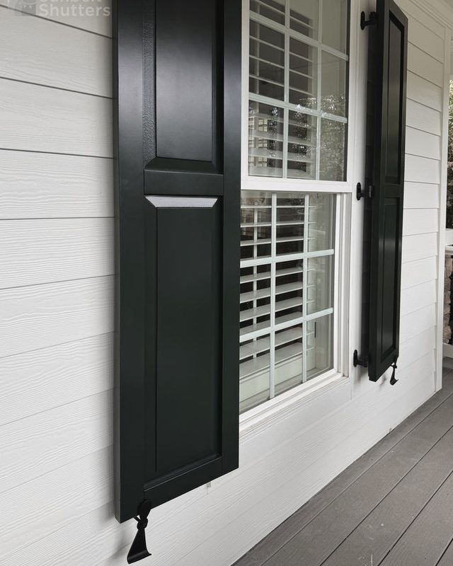Black custom raised panel shutter with a shutter dog on a white lap-siding home