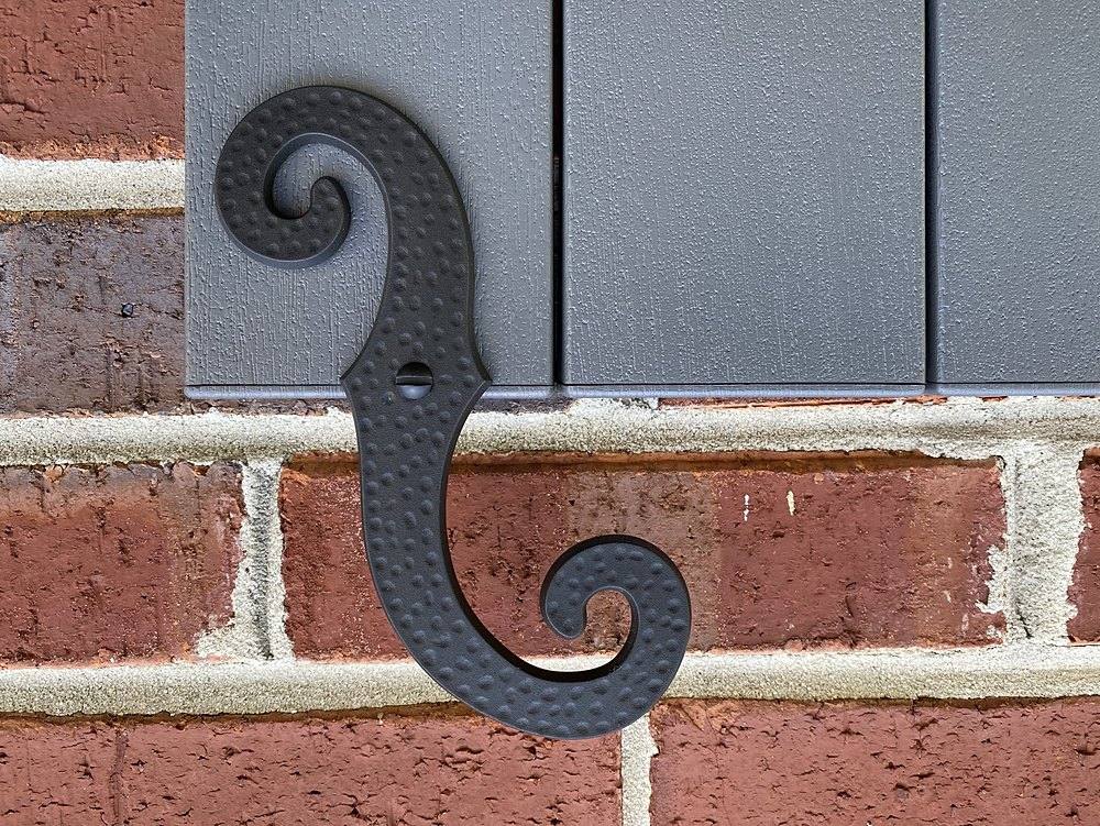 S-scroll shutter dog tieback installed beside an exterior shutter
