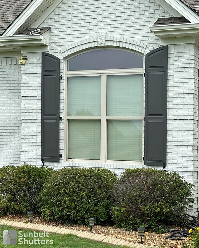 Arched top raised panel shutters on white brick
